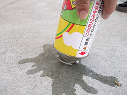 スプレー缶を逆さにしてコンクリートに押し付けている写真