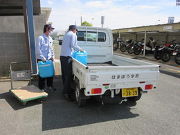 写真：従業員が次亜塩素酸水を軽トラックに運ぶ様子