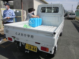 写真：次亜塩素酸水を軽トラックに運ぶ様子