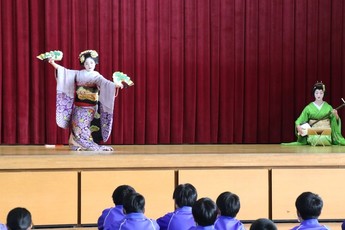 舞妓さんが生徒たちの前で踊っている写真